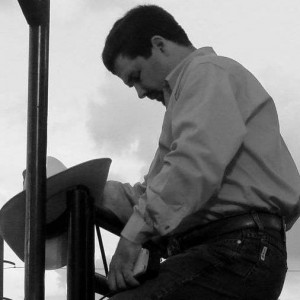 Mack Ginn standing with his head bent in prayer atop the bucking shoots